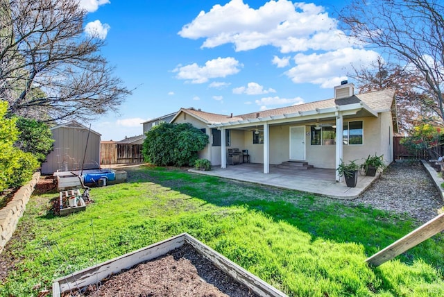 back of property with a storage unit, a yard, and a patio