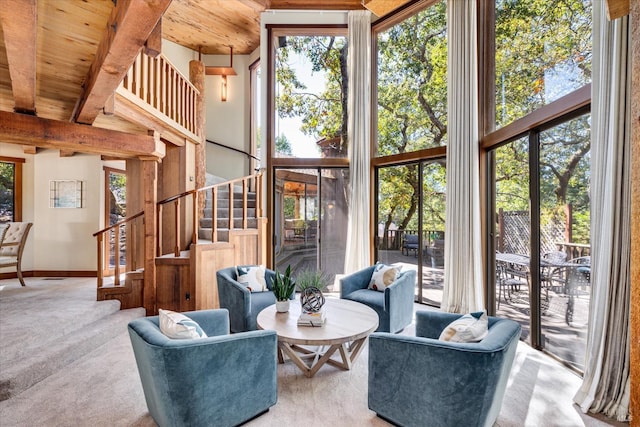 carpeted living room with wooden ceiling, beam ceiling, and a high ceiling