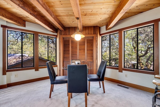 carpeted dining room with wood ceiling, a healthy amount of sunlight, and beam ceiling