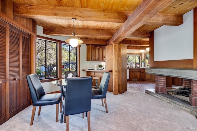 carpeted dining space featuring beam ceiling and wood ceiling