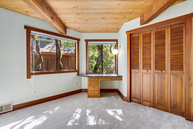 unfurnished bedroom with built in desk, vaulted ceiling with beams, light colored carpet, a closet, and wooden ceiling