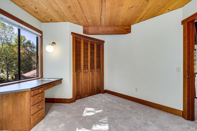 unfurnished office featuring light colored carpet, beamed ceiling, and wood ceiling