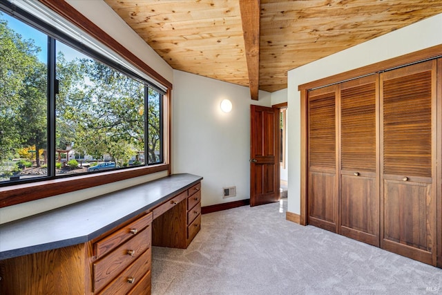 unfurnished office with wood ceiling, built in desk, vaulted ceiling with beams, and light colored carpet