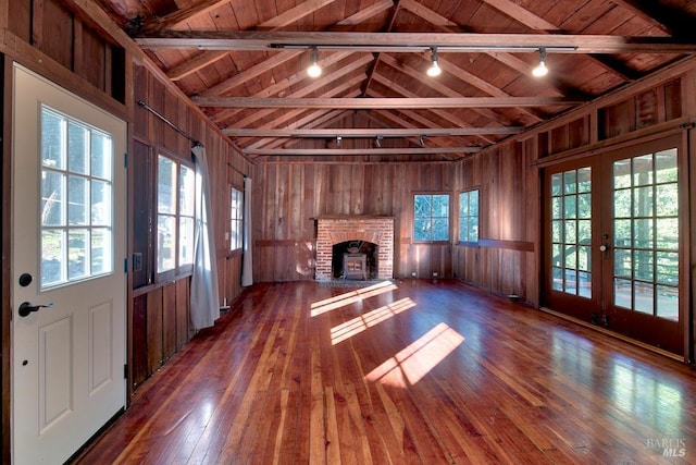 unfurnished living room featuring dark wood-type flooring, a healthy amount of sunlight, wood ceiling, and wooden walls