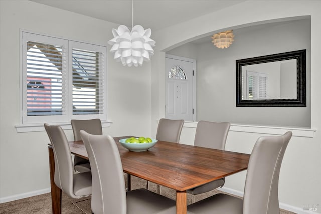 carpeted dining room featuring a notable chandelier