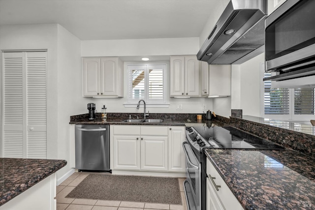 kitchen with sink, wall chimney range hood, white cabinets, and appliances with stainless steel finishes