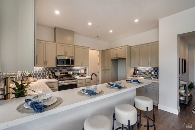 kitchen featuring stainless steel appliances, a kitchen breakfast bar, backsplash, and dark hardwood / wood-style flooring