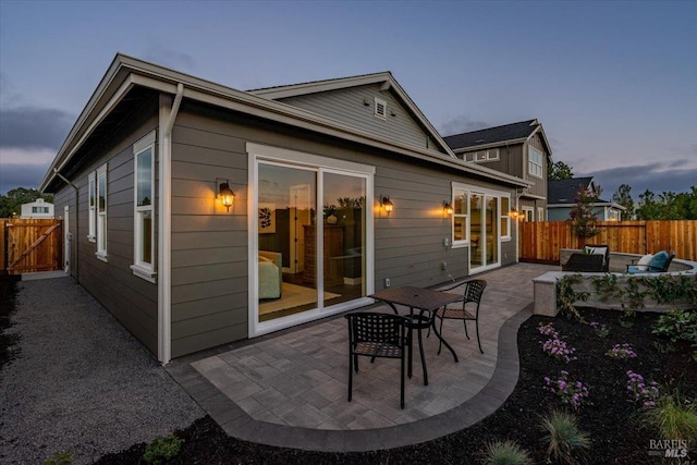 back house at dusk with an outdoor living space and a patio area