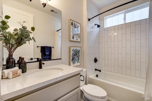 full bathroom featuring vanity, tiled shower / bath, and toilet