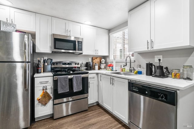 kitchen with stainless steel appliances, sink, white cabinets, and dark hardwood / wood-style floors