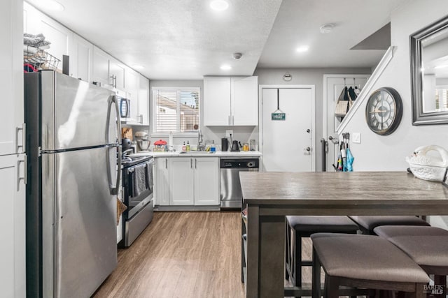 kitchen featuring sink, white cabinetry, a textured ceiling, dark hardwood / wood-style flooring, and stainless steel appliances