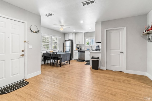 foyer entrance with ceiling fan, a healthy amount of sunlight, light hardwood / wood-style floors, and a textured ceiling