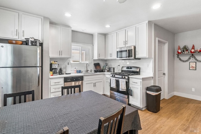 kitchen with sink, white cabinetry, appliances with stainless steel finishes, light hardwood / wood-style floors, and decorative backsplash