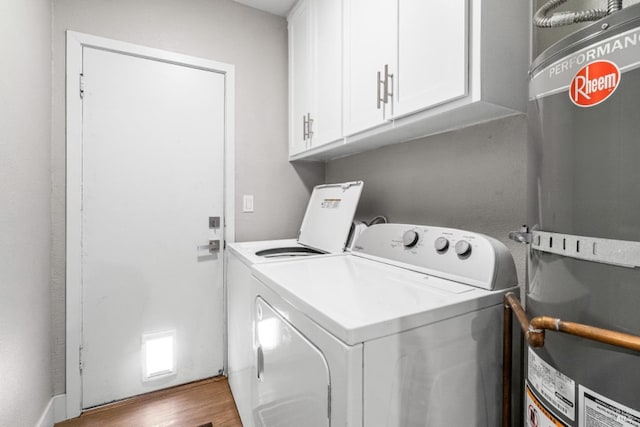 washroom featuring cabinets, secured water heater, hardwood / wood-style floors, and washer and dryer