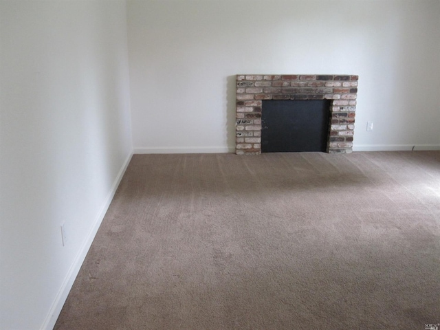 unfurnished living room with a brick fireplace and carpet