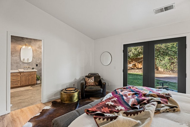 bedroom with sink, ensuite bath, light hardwood / wood-style flooring, access to outside, and vaulted ceiling