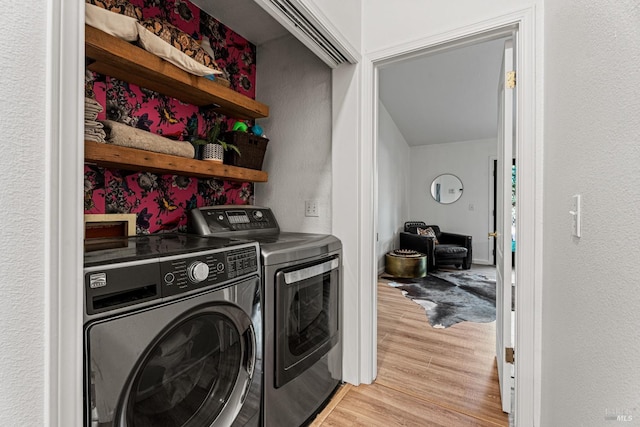 laundry room featuring washing machine and dryer and light hardwood / wood-style flooring