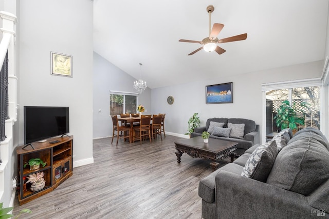 living room featuring ceiling fan with notable chandelier, light hardwood / wood-style flooring, and high vaulted ceiling