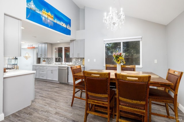 dining room featuring high vaulted ceiling, a chandelier, and light wood-type flooring