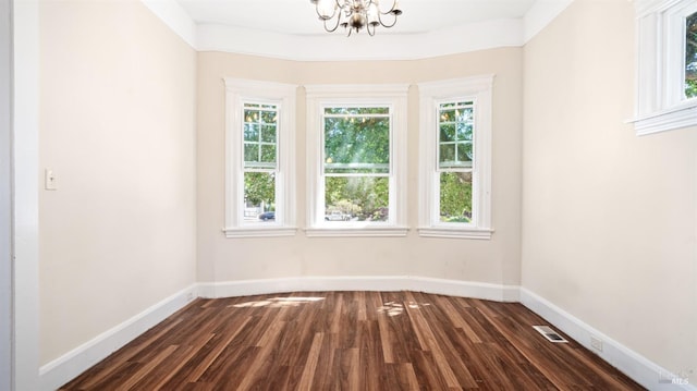 unfurnished room featuring dark wood-type flooring and a notable chandelier