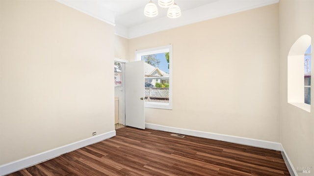 unfurnished room featuring ornamental molding, dark hardwood / wood-style floors, and a chandelier