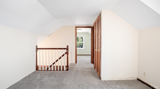 hallway with lofted ceiling and light carpet