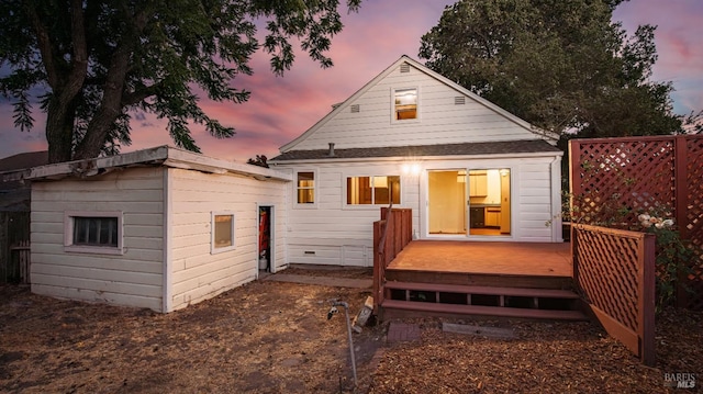 back house at dusk featuring an outdoor structure and a deck