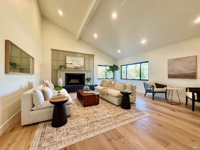 living area with baseboards, high vaulted ceiling, a fireplace with raised hearth, beamed ceiling, and light wood-type flooring