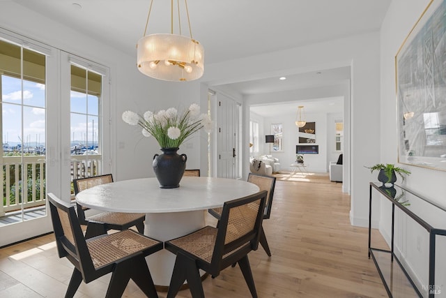 dining room featuring light wood-type flooring, a fireplace, and baseboards