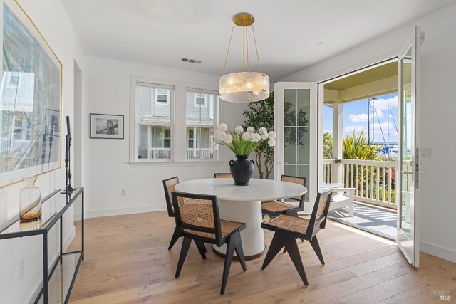 dining room with a healthy amount of sunlight, light wood-style floors, and visible vents