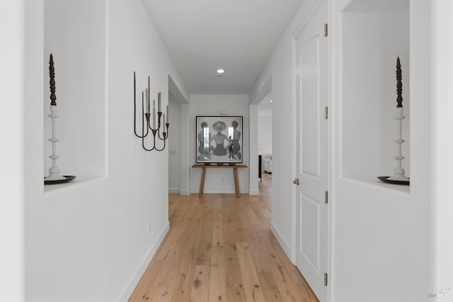 hall featuring light wood-type flooring, baseboards, and recessed lighting