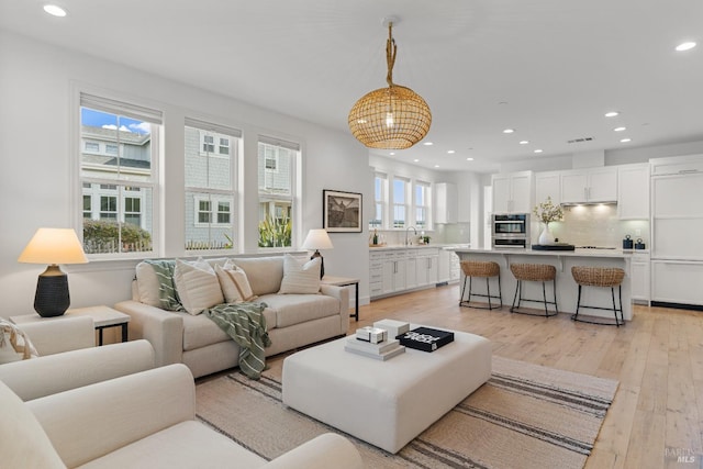 living room with recessed lighting, visible vents, and light wood-style flooring