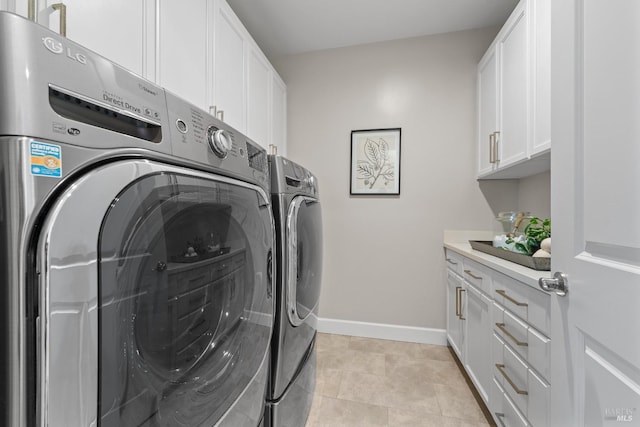 clothes washing area featuring light tile patterned flooring, cabinet space, baseboards, and separate washer and dryer