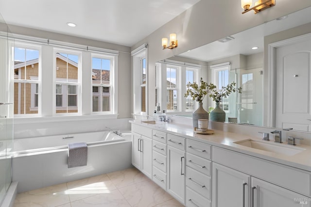 full bathroom featuring marble finish floor, double vanity, a sink, and a wealth of natural light