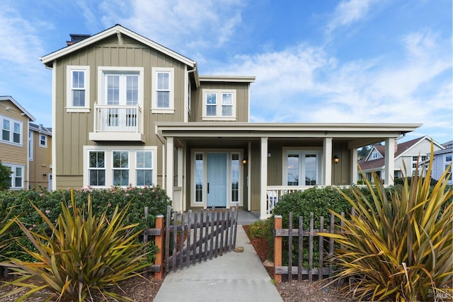 view of front of home with a fenced front yard, a gate, a porch, and board and batten siding