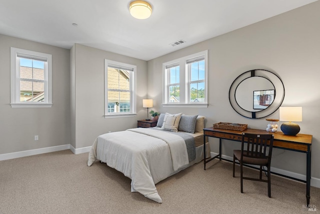 bedroom featuring light carpet, visible vents, baseboards, and multiple windows