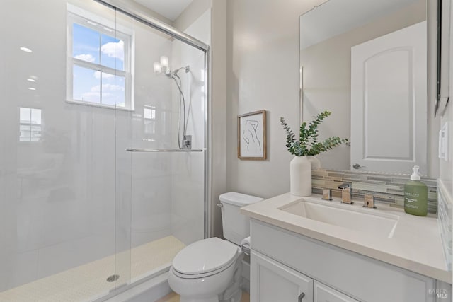 bathroom featuring toilet, a stall shower, tasteful backsplash, and vanity