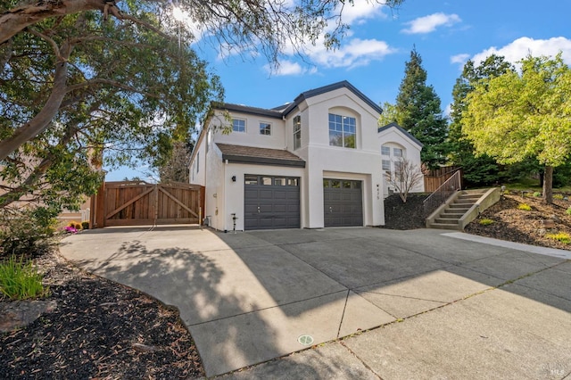 traditional-style house with stairs, concrete driveway, an attached garage, and a gate