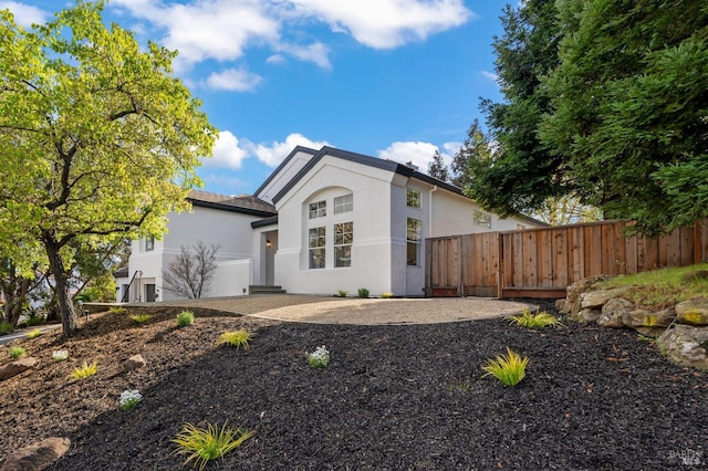 view of front of home featuring stucco siding, fence, and a patio