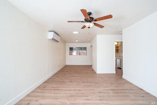 empty room featuring an AC wall unit, sink, ceiling fan, and light hardwood / wood-style flooring