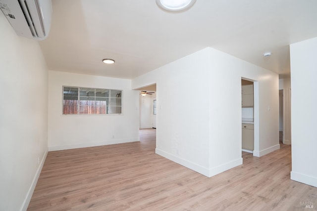 empty room featuring ceiling fan, a wall mounted air conditioner, and light hardwood / wood-style flooring