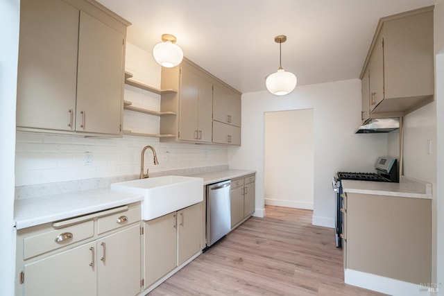 kitchen with sink, appliances with stainless steel finishes, tasteful backsplash, decorative light fixtures, and light wood-type flooring