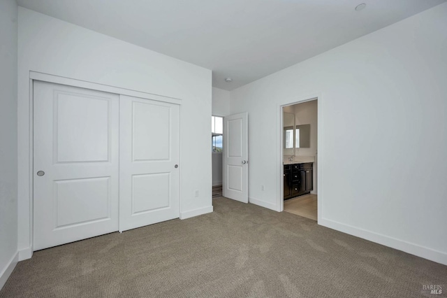 unfurnished bedroom with ensuite bathroom, carpet, and a closet