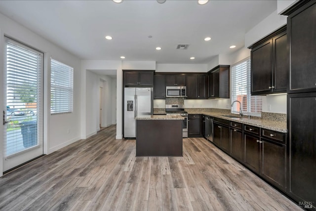 kitchen featuring sink, light hardwood / wood-style flooring, appliances with stainless steel finishes, a kitchen island, and a healthy amount of sunlight