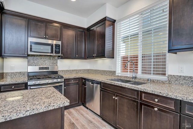 kitchen featuring dark brown cabinetry, appliances with stainless steel finishes, sink, and light hardwood / wood-style flooring