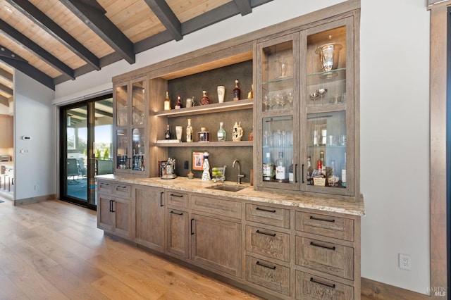 bar featuring sink, vaulted ceiling with beams, light stone counters, light hardwood / wood-style floors, and wooden ceiling