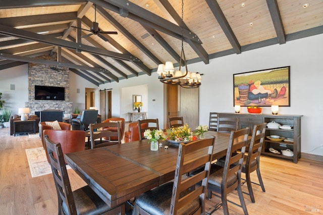 dining room with a fireplace, light hardwood / wood-style floors, wooden ceiling, and beamed ceiling