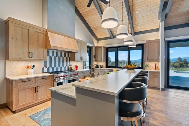 kitchen with range with two ovens, a center island with sink, pendant lighting, and decorative backsplash