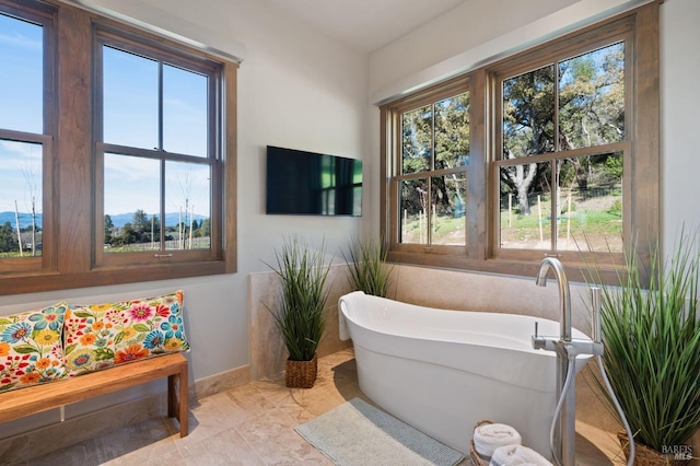 bathroom with tile patterned flooring, a wealth of natural light, and a tub to relax in