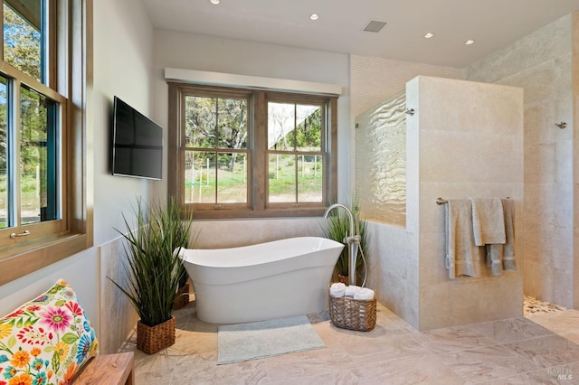 bathroom featuring tile walls and a tub to relax in